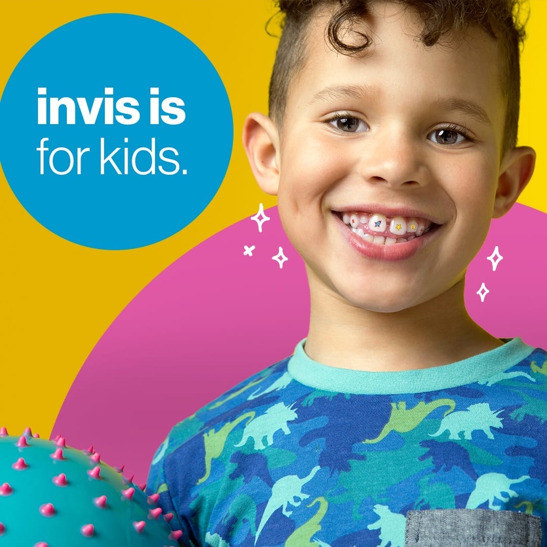 Smiling young boy with curly hair shows orthodontic aligners on his teeth. Text reads, "invis is for kids." Colorful background with playful elements.