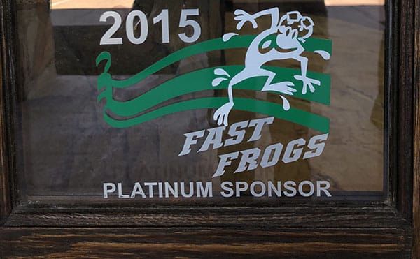 Sticker on glass reads "2015 FAST FROGS PLATINUM SPONSOR" with a white frog and green stripes in the background, highlighting Wildflower Sponsors' support.